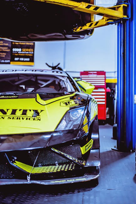 Close-up of a yellow racing car in a garage setting with tools visible.