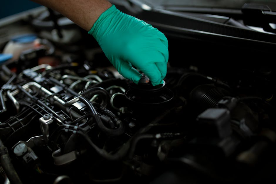 Mechanic wearing gloves changing engine oil in a vehicle. Close-up of a hand working on car maintenance.