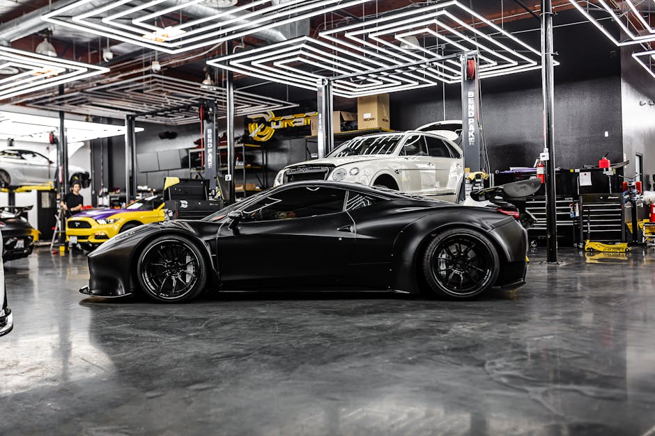 A sleek black sports car and luxury vehicles in a high-end auto repair shop interior.
